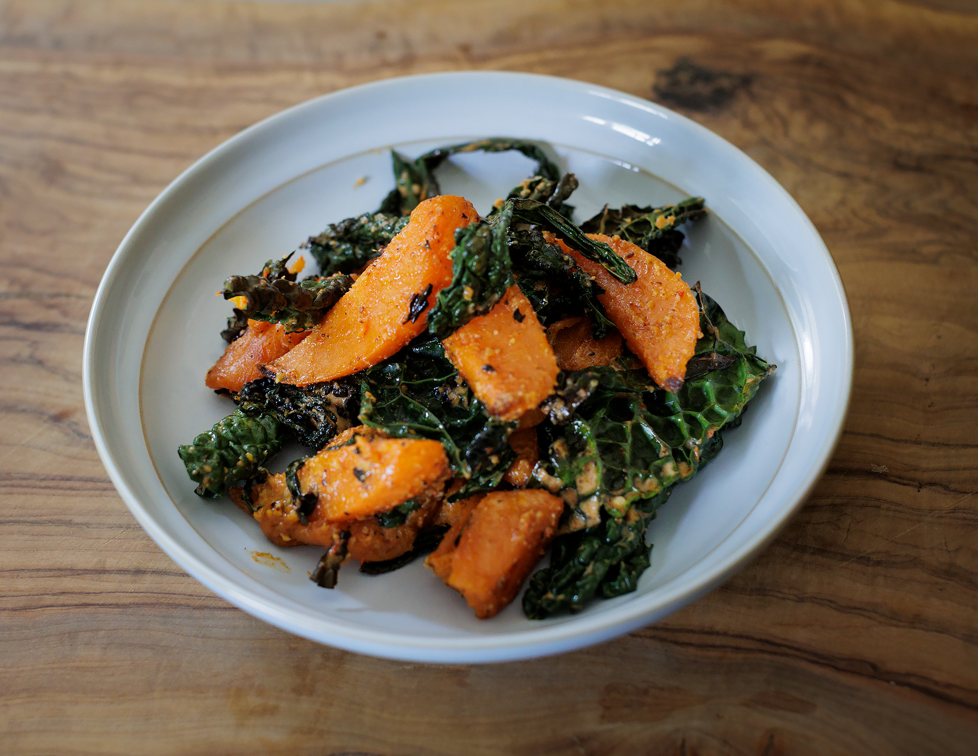 sweet potato and kale bowl with spicy miso dressing served in a white bowl